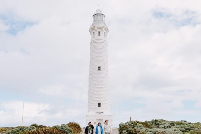 Three people walking in front of Cape Leeuwin Lighthouse