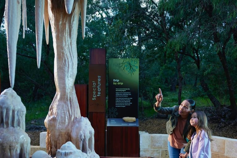 Young girl and women looking and pointing to a sculpture at the Ancient Land Experience at Ngilgi Cave.