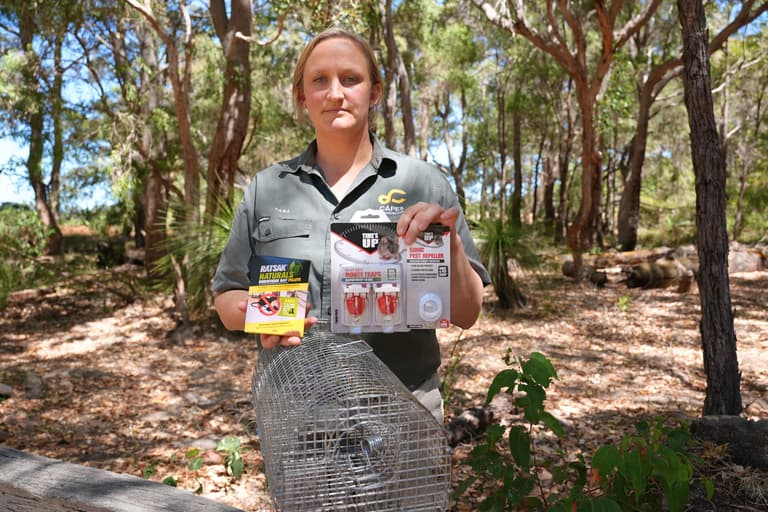 Capes Raptor Centre staff member holding rodent control products beside a live capture trap