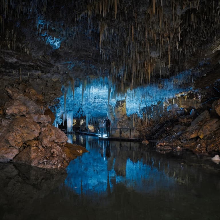 People admiring the tranquil lake reflections and stunning formations inside Lake Cave
