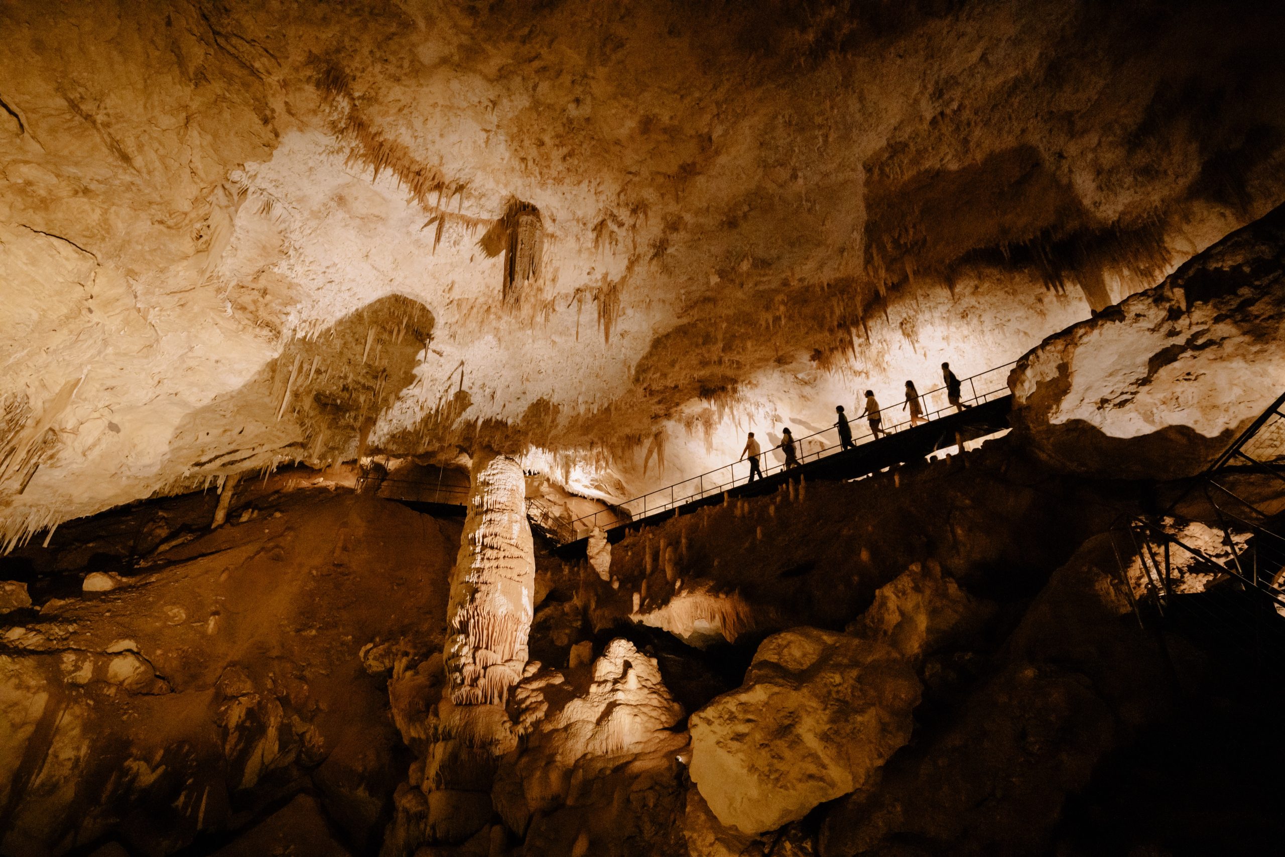 Inside Jewel Cave, a tour group can be seen walking across a high viewing platform